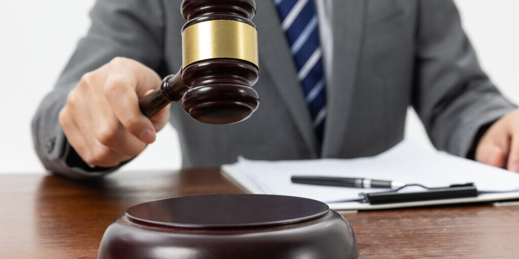 A closeup shot of a person holding a gavel on the table
